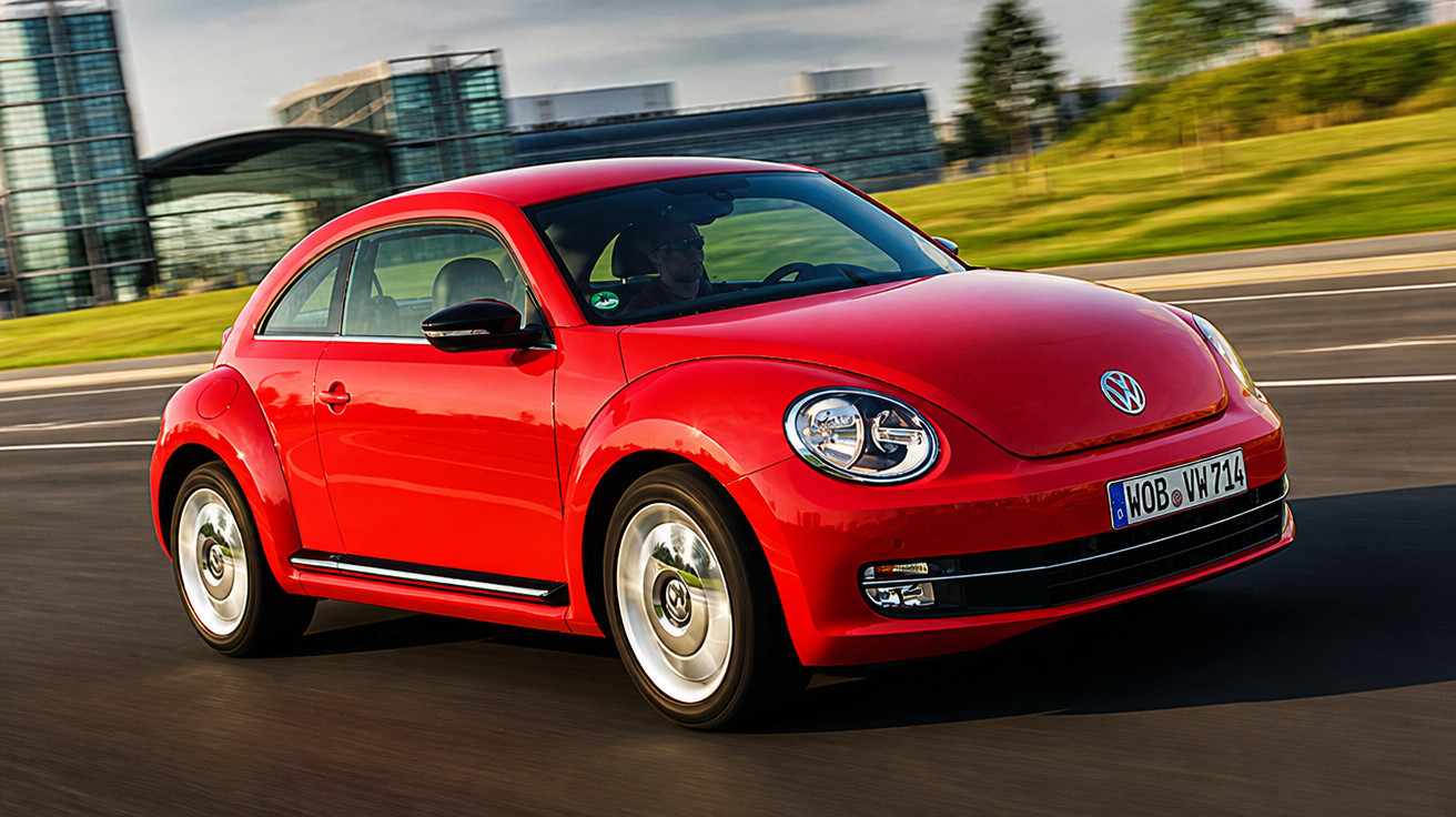 Carro vermelho Volkswagen Fusca em movimento em estrada urbana com prédios ao fundo.