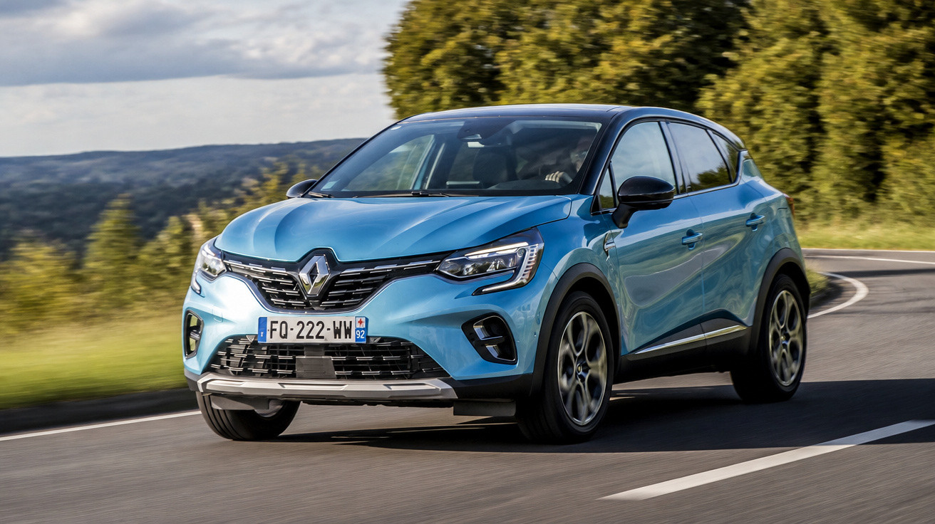 Carro SUV azul da Renault trafegando em estrada sinuosa com árvores ao fundo.