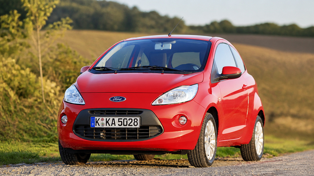 Carro Ford vermelho estacionado em estrada de terra com paisagem rural ao fundo.